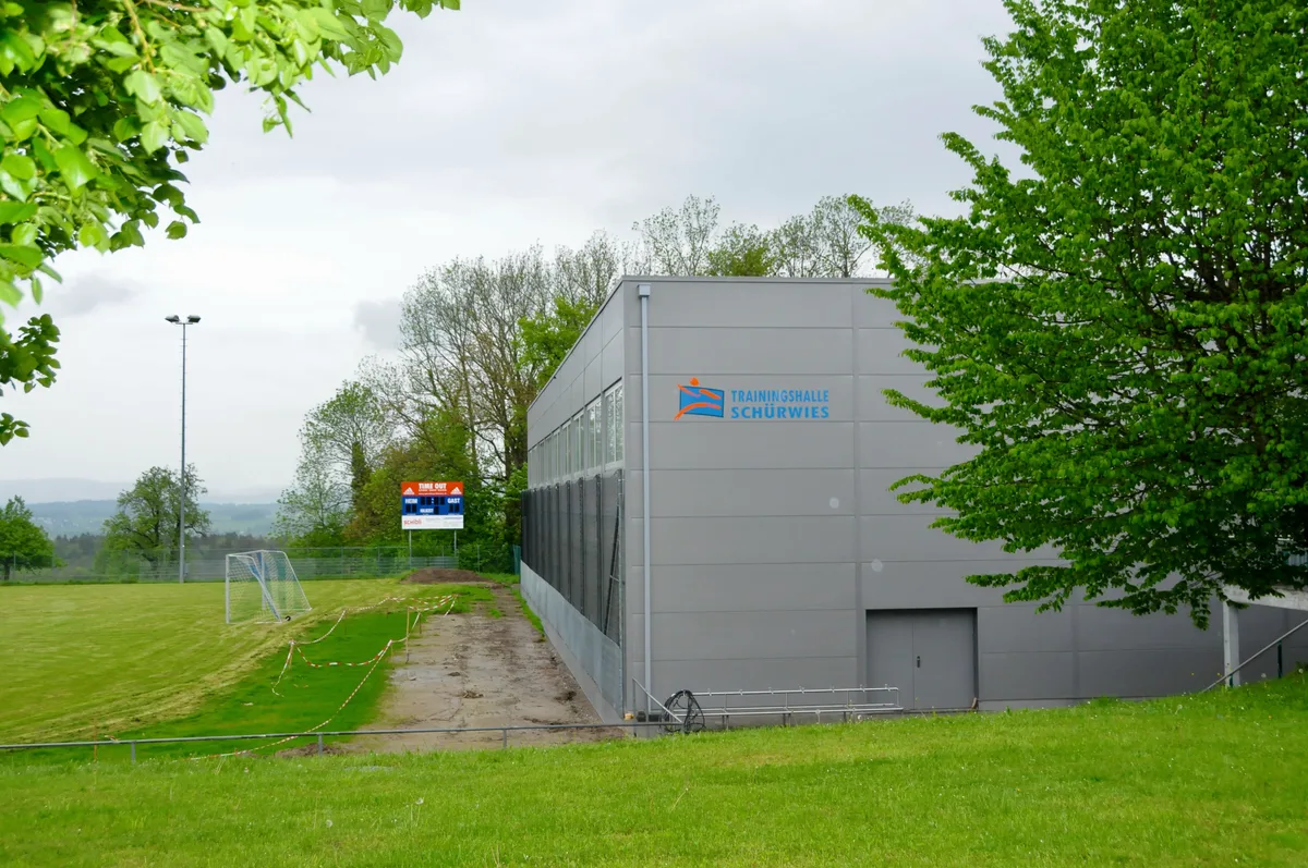 Man sieht die neue Trainingshalle Schürwies in Egg zwischen Fussball- und Tennisplatz.